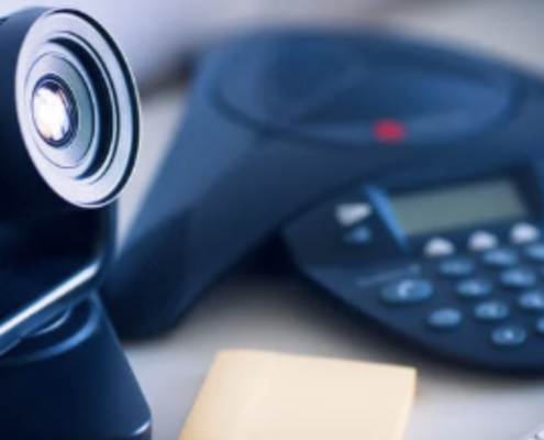 A close-up of a video conferencing camera and VoIP phone system on a desk, illustrating the integration of cloud VoIP in Dallas businesses for seamless communication.